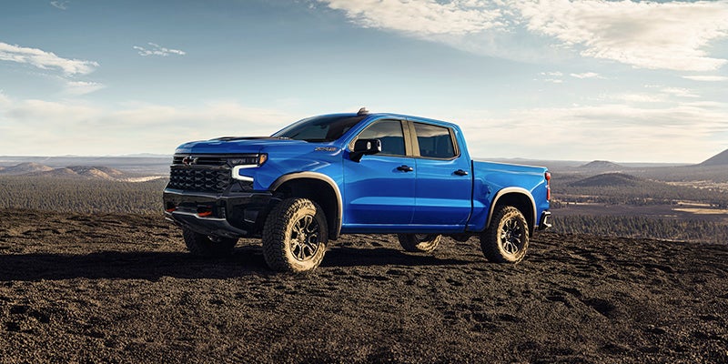 Chevrolet Silverado-LD parked on rugged terrain with mountains in the background